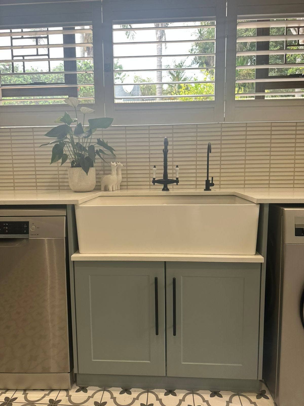 White farmhouse sink fitted into custom grey cabinets